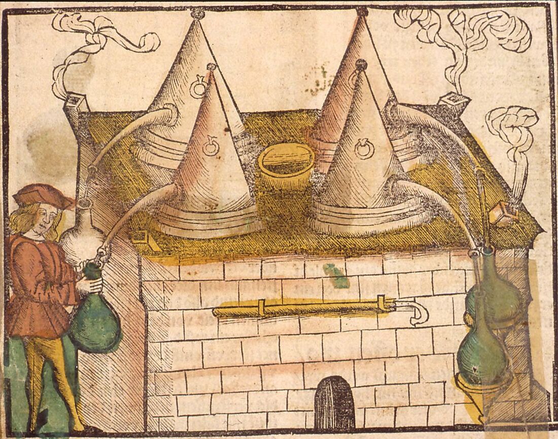 Bois gravé rehaussé de couleurs : deux grands alambics à chapiteau conique posés sur un fourneau de briques maçonné, leurs cols conduisant vers des bonbonnes de verre ; à gauche, un distillateur en pourpoint recueille le distillat dans une dame-jeanne.